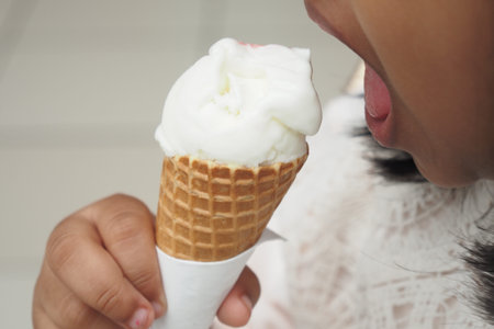 Child Hand Holding Vanilla Ice Cream in A Waffle Cone.
