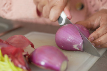 women hand with knife cutting red onionの写真素材