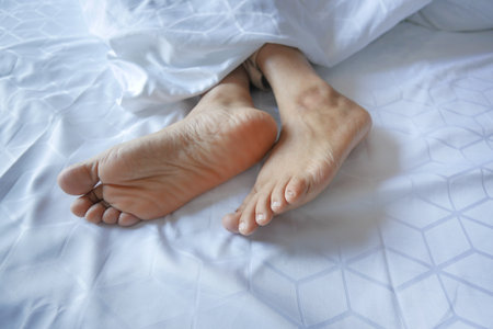 young Woman lying with bare feet in bed,の写真素材