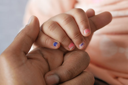 father holding hand of baby child, close up .