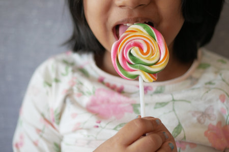 child is licking colorful candy on stick,の写真素材