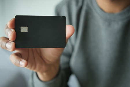 young men holding a black color credit cardの写真素材