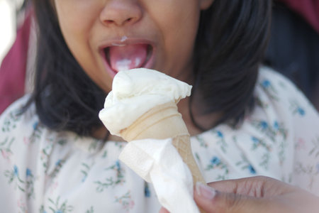 Child Hand Holding Vanilla Ice Cream in A Waffle Cone.の写真素材