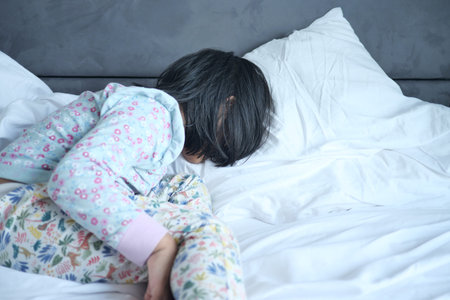 a upset child girl sleeping on bedの写真素材