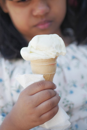 Child Hand Holding Vanilla Ice Cream in A Waffle Cone.