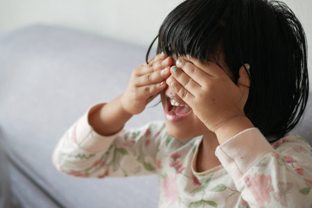 a upset child girl cover her face with hand