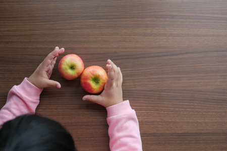 child hand hold apples on wooden table