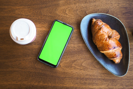 top view of Coffee croissant and smart phone with green screen
