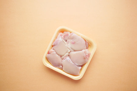 raw breast chicken meat in a plastic packet on orange backgroundの写真素材