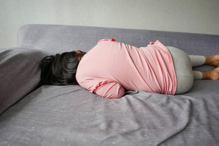 a upset child girl cover her face with hand in sofa at homeの写真素材