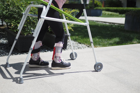 child with walking frame and knee orthosis outdoorの写真素材