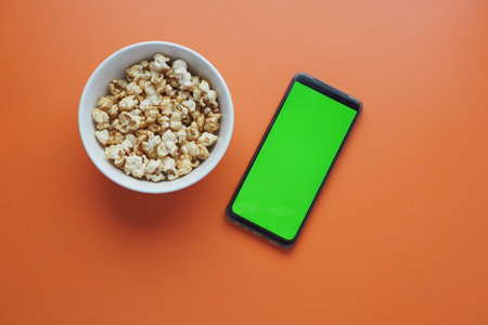 top view of smart phone and popcorn on tableの写真素材