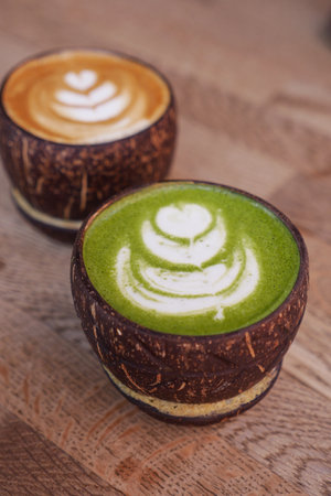Latte and matcha latte in a coconut cup on tableの写真素材