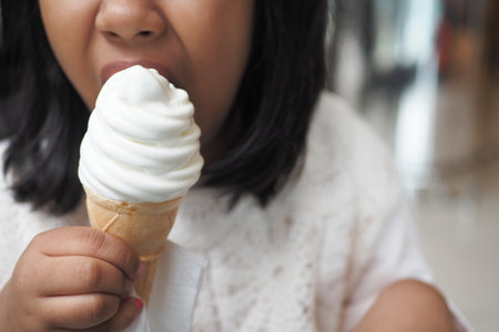 Child Hand Holding Vanilla Ice Cream in A Waffle Cone.の写真素材
