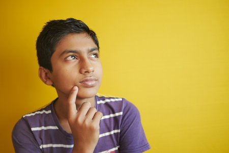 thoughtful boy looking away while sitedの写真素材