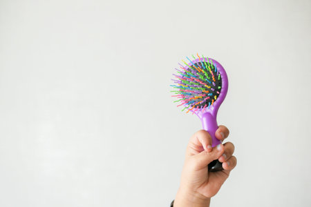 child hand holding a colorful hair brush at home ,