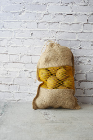 potatoes in a sack bag on tableの写真素材