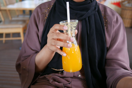 women drinking fresh orange juice sitting on cafeの写真素材