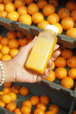 women holding a bottle of orange juice against against fruit backgroundの写真素材