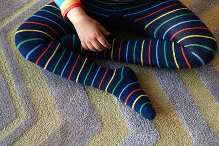 top view of child with Colorful striped socks sitting on carpetの写真素材