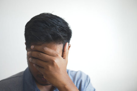Close up of sad man covering face with hand.