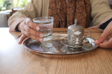 a cup of turkish coffee and glass of water on tableの写真素材