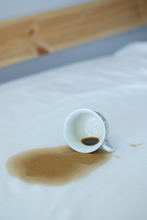 cup of coffee spilled on gray white bed