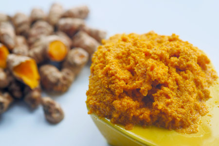 turmeric root and paste in a bowl on white background