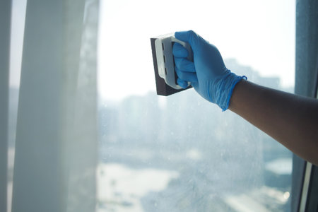 person hand in gloves cleaning window glassの写真素材