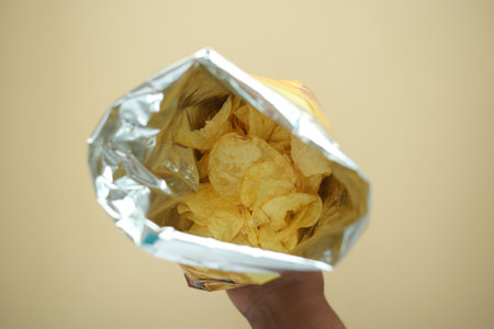 holding a open potato chips packetの写真素材