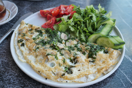 Plain Egg Omelette served with fresh herbs on a plate on tableの写真素材