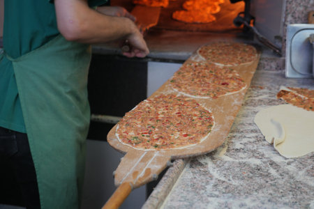 the chefs hands form a round pizza base from the dough with his hands.
