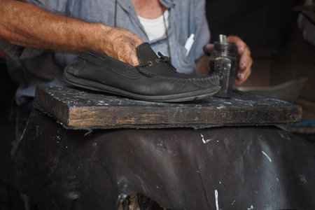 A cobblers hands mending shoe stitching with needle