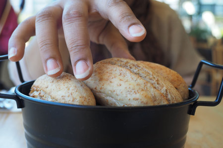 women hand pick baked bun on table