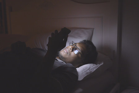 The man lay on the bed and phone at nightの写真素材