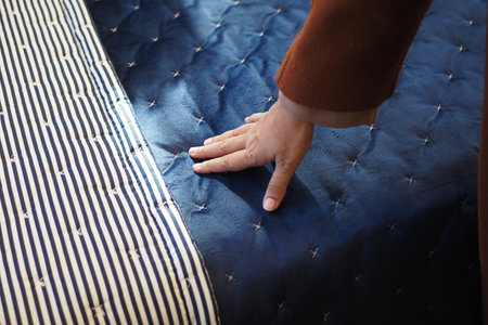 Hand touching and pressing orthopedic mattress on bed.の写真素材