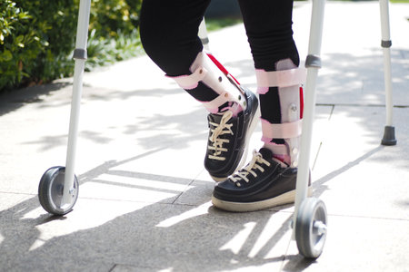 child with walking frame and knee orthosis outdoorの写真素材