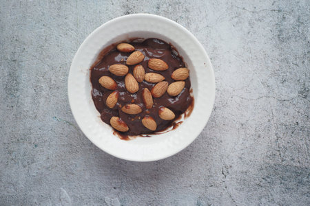 dark chocolate cream pouring on almond nut on whiteの写真素材