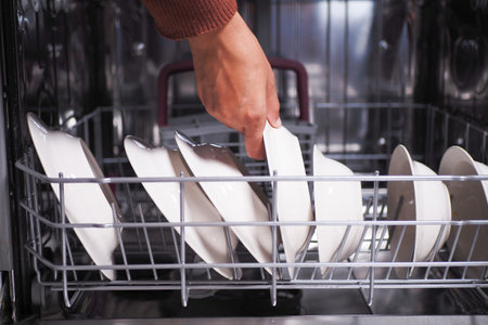 A young woman opens takes out clean white utensils.の写真素材