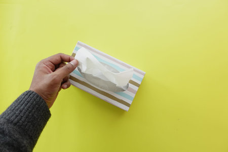 hand pull out a piece of tissue from tissue paper box