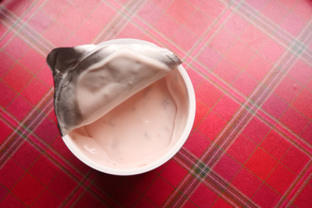 fresh yogurt in a plastic container and spoon on tableの写真素材