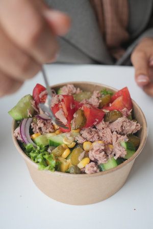 spoon pick tuna salad from a bowl on tableの写真素材