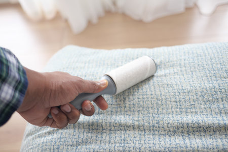 using an adhesive roller to remove lint and fluff from a bed .の写真素材