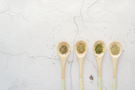 Four wooden spoons with various spices on a white tableware surfaceの写真素材