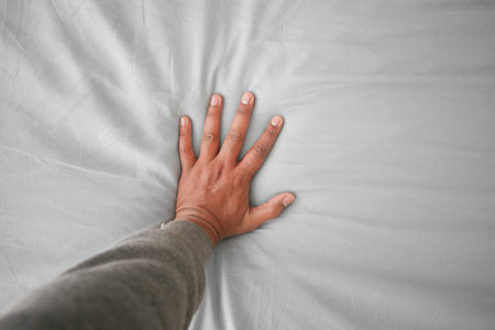 Hand touching and pressing orthopedic mattress on bed.の写真素材