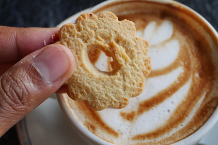 pouring sweet cookies in a coffee mug on wooden table