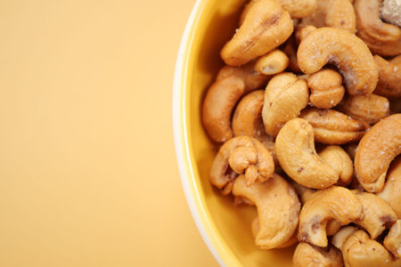 cashew nuts in a small bowl on yellow color background
