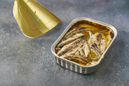 open tin of sardines on white tiles background.