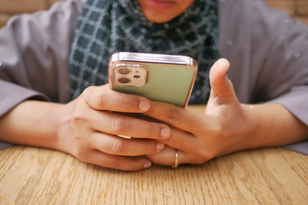 women hand holding smart phone sitting on cafe