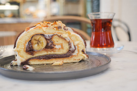 A slice of cake on serveware next to a glass of tea drinkware